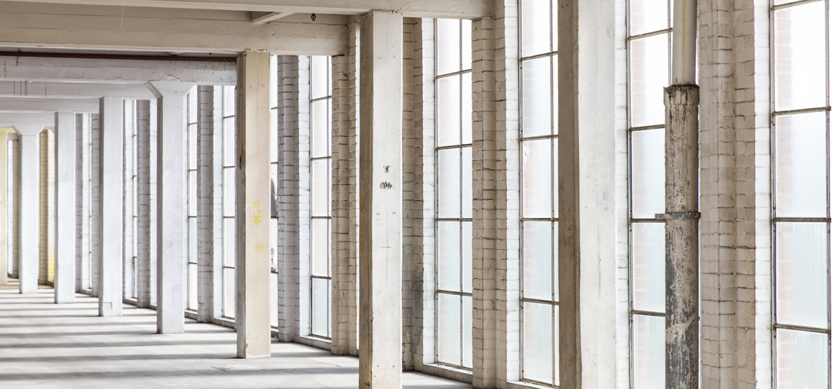 Interior Natural Light Windows Bright industrial space with large windows and concrete pillars, maximizing natural light.