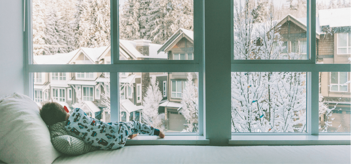 Child Looking Out Window At Winter Snow Feature Image - winter home