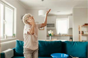 Elderly woman gesturing towards a ceiling leak in her living room