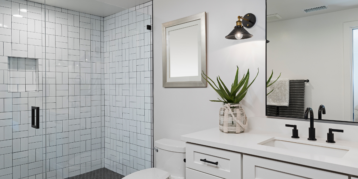 Modern Bathroom Subway Tile Vanity A bright, modern bathroom showcasing high-value upgrades, including a white vanity with matte black hardware, a black wall sconce, and a glass-enclosed shower with white subway tile.