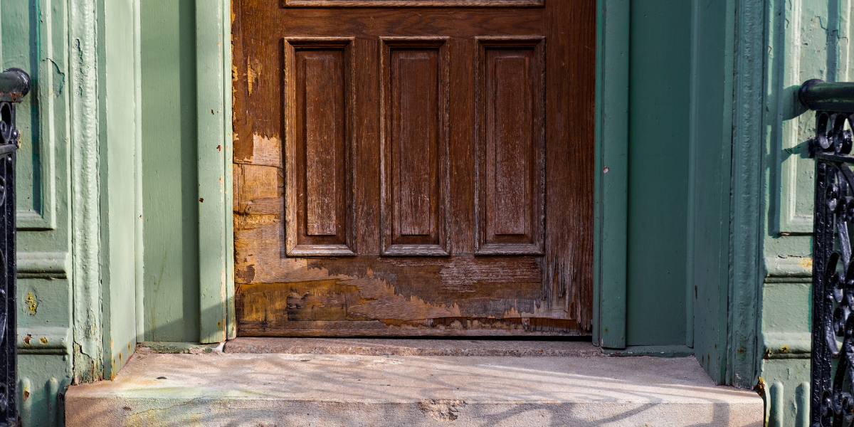Worn Wooden Door Peeling Paint Worn wooden front door with peeling paint, causing door closure issues.